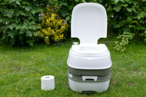 Camping toilet, Eine chemische Campingtoilette und eine Toilettenpapierrolle nebeneinander auf einem Rasen