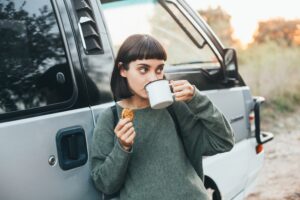 Girl eating a road trip snack outside a campervan