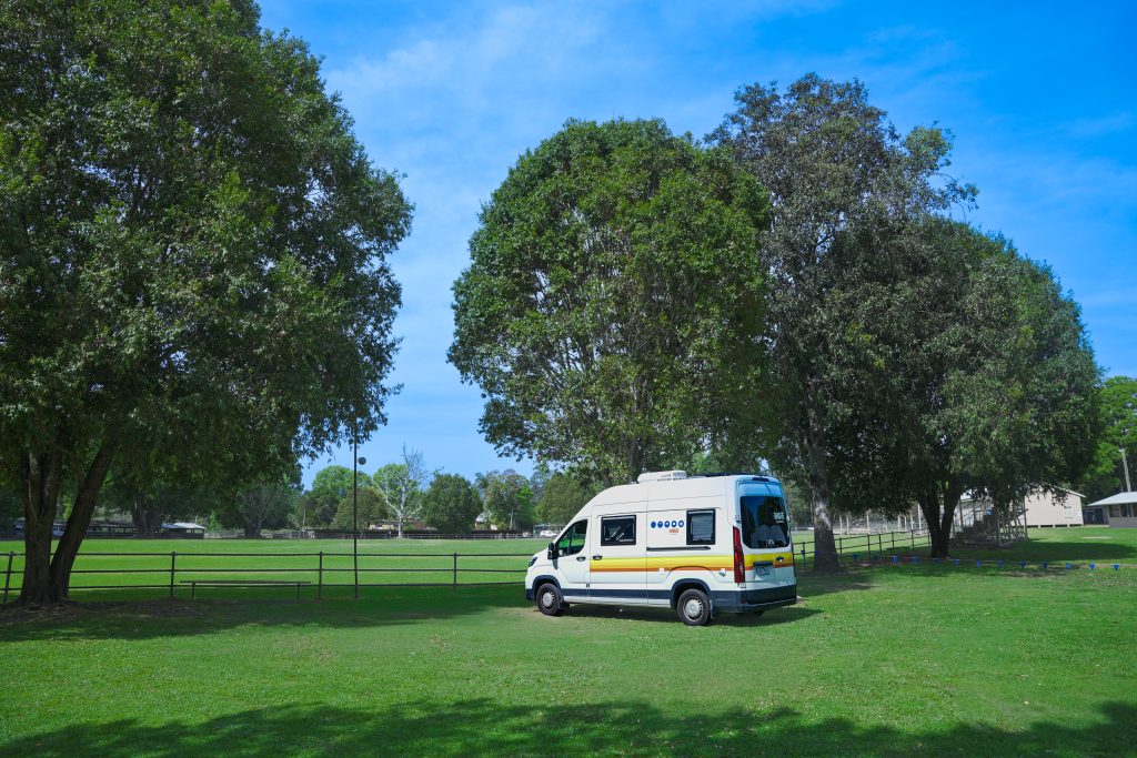 Indie Campers campervan parked under trees at a campsite