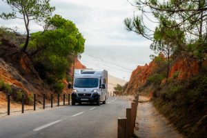 Traveler holding an international driver’s permit next to a campervan before starting a road trip abroad.