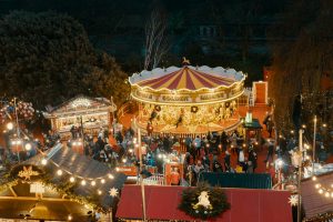 Edinburgh Christmas Market at night, with a lit-up carousel and wooden chalets in Princes Street Gardens