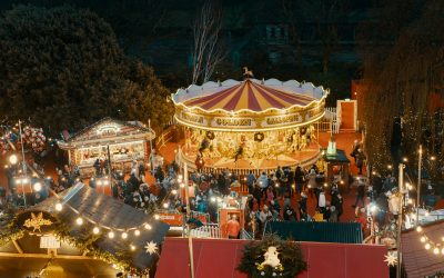 Edinburgh Christmas Market at night, with a lit-up carousel and wooden chalets in Princes Street Gardens