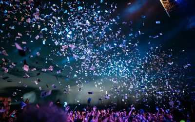 Festival crowd celebrating under falling confetti and stage lights