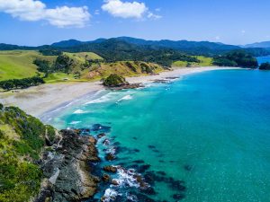 Aerial view of a turquoise bay and beach on New Zealand’s North Island coast in summer