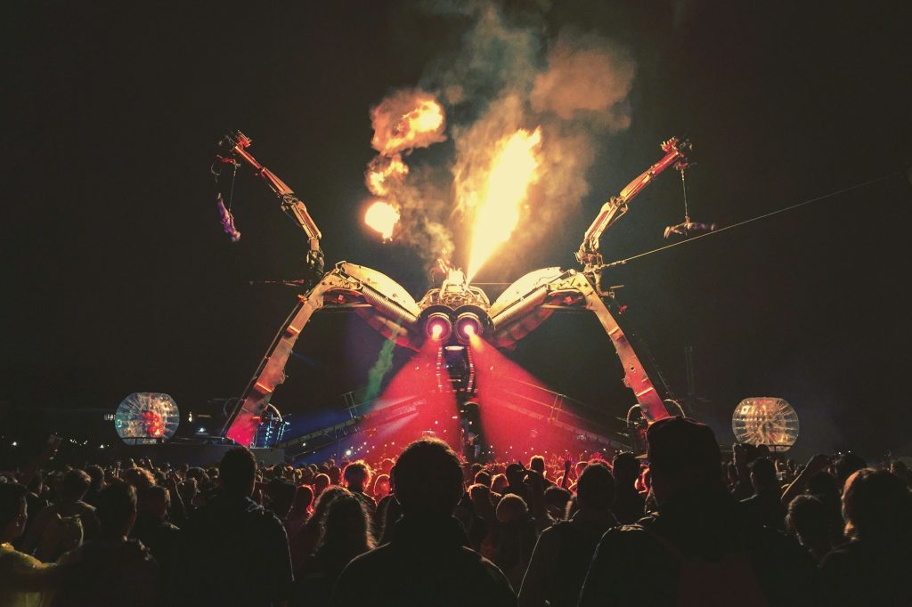 Crowd watching flames shoot from the giant mechanical spider at Glastonbury’s Arcadia stage at night